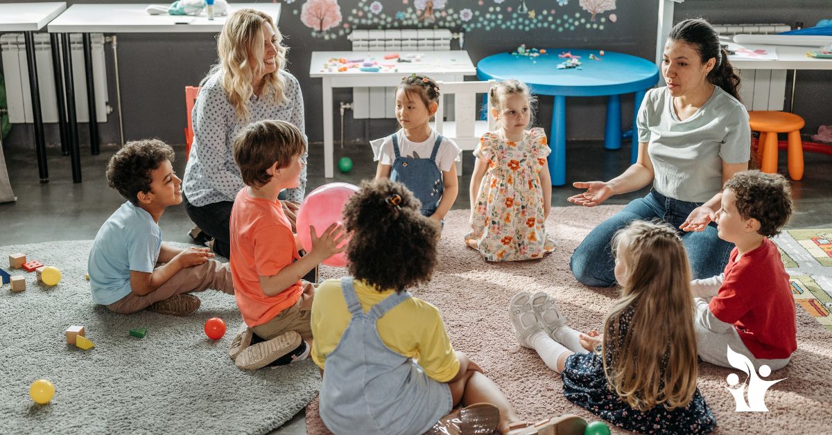Image is of two female teachers on the floor with young students