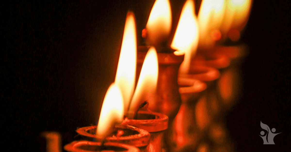 Photograph of a lit menorah with the first candle extinguished