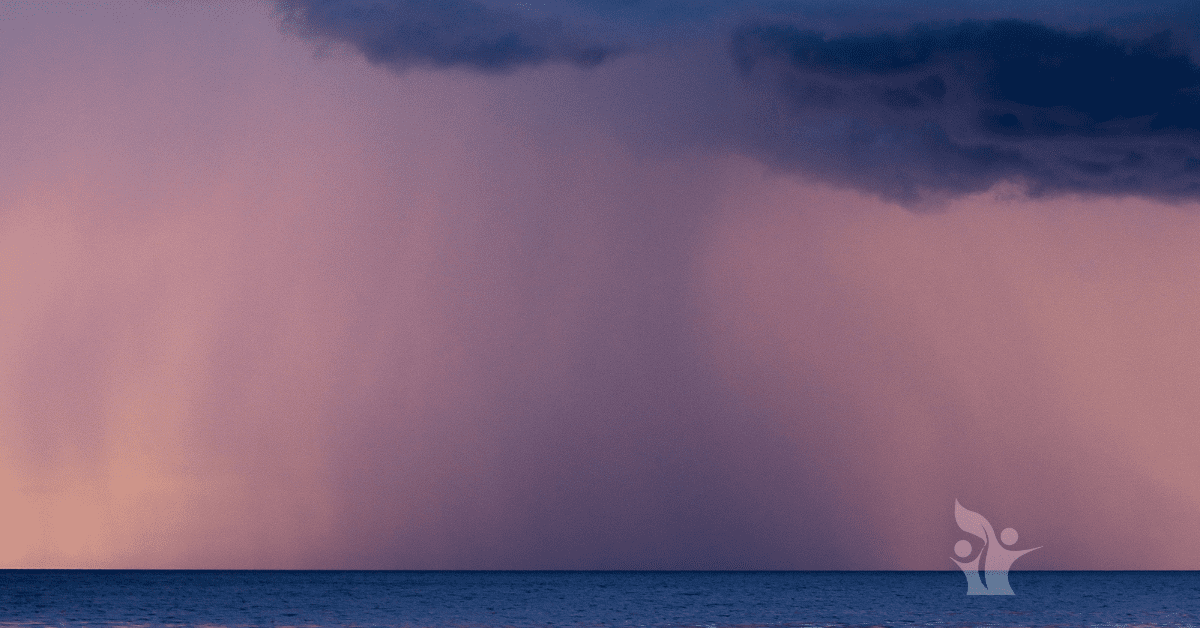 Photograph of a dark cloud pouring rain over the ocean