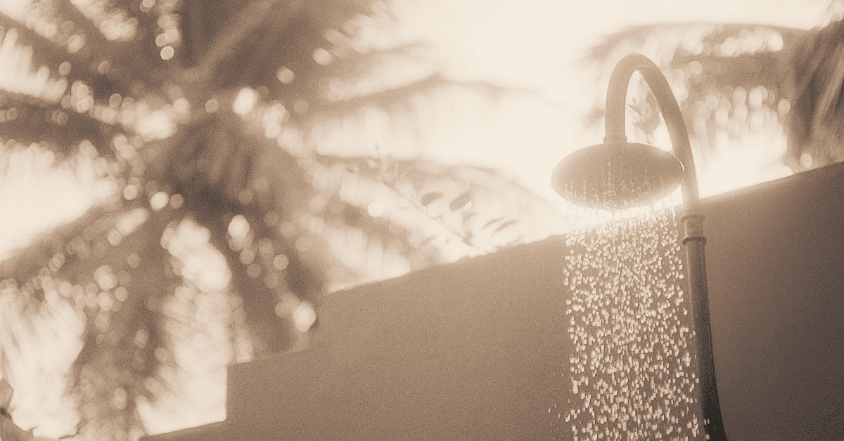 Sepia toned photograph of an outdoor shower with palm trees in the background
