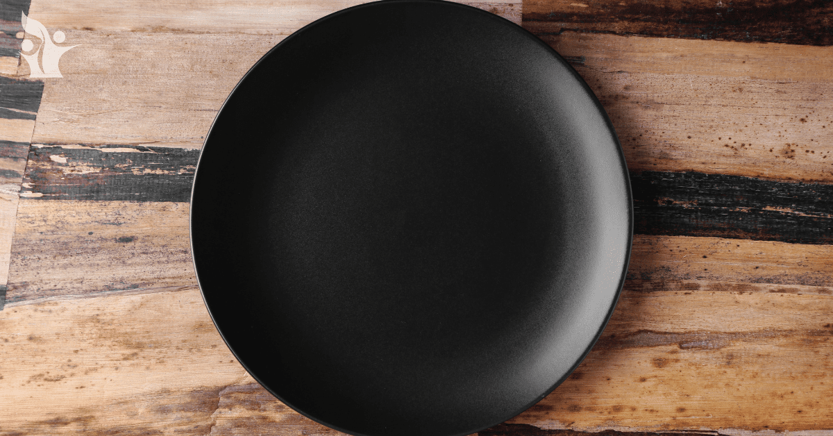 Photograph of a black empty plate on a rustic wood table