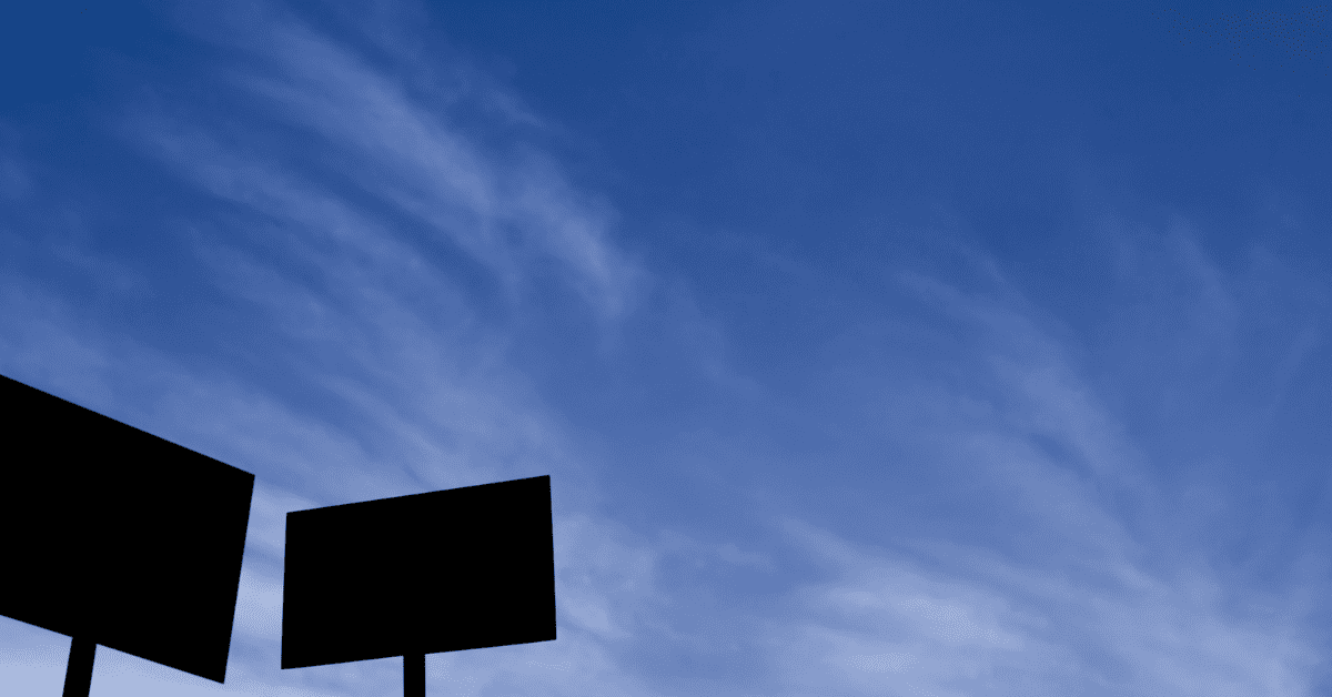 Photograph of a cloudy sky with the silhouette of 2 picket signs