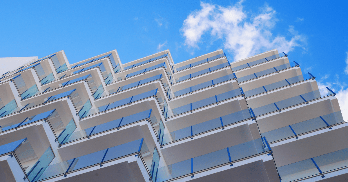 Photograph facing up a geometric building with a blue sky