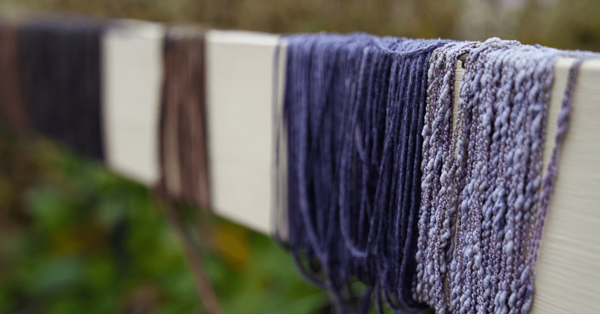 Different colours of thin rope wrapped around a white fence post